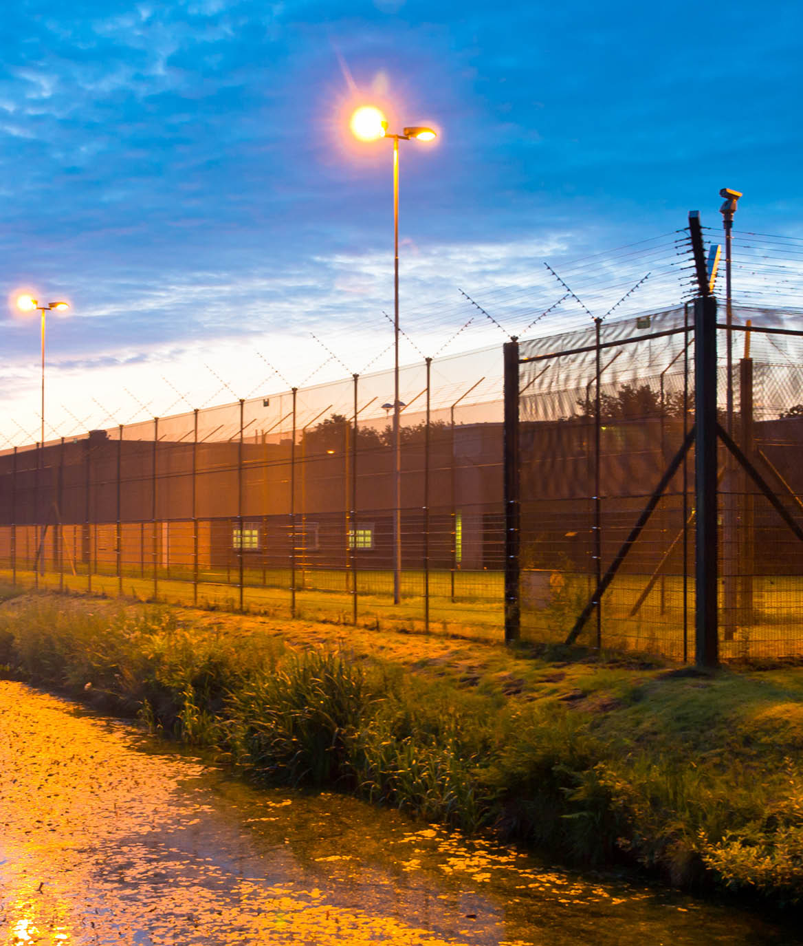European Prison Fence with Ditch at Dawn