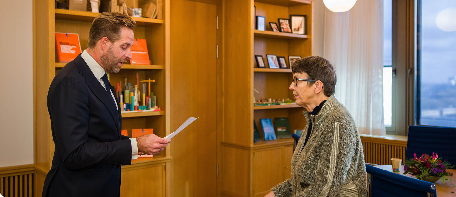 Minister Hugo de Jonge leest een brief voor aan Jetta Klijnsma.